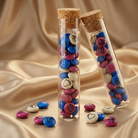 Deux tubes en verre contenant des M&M'S personnalisés de michelangelo intimo Sur une fine soie champagne, comme un doux présent.