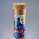 Gros plan sur le tube en verre transparent avec son bouchon en liège naturel véritable et ses lentilles en chocolat M&M'S imprimées.
